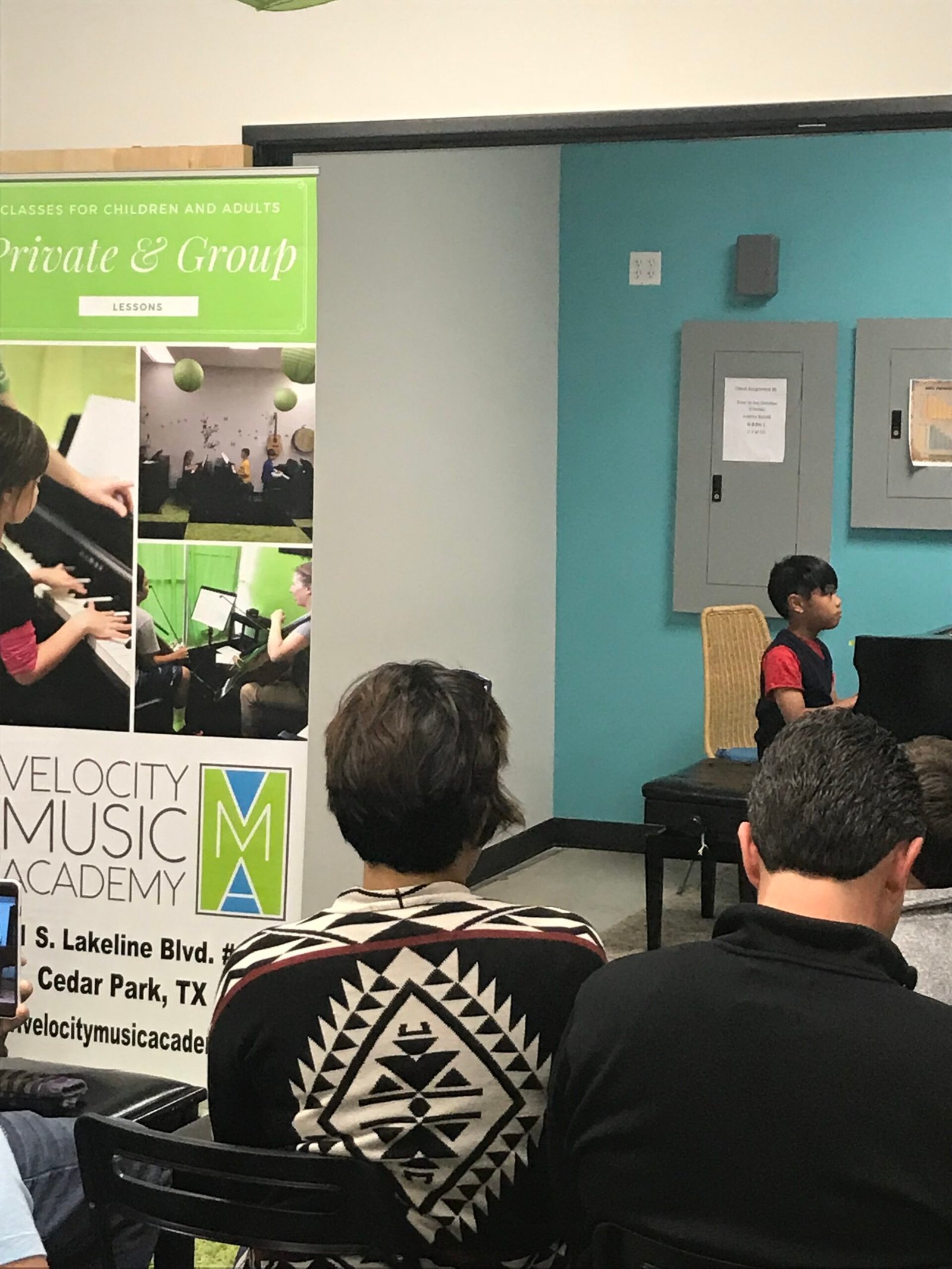 Child playing a piano recital with a small audience