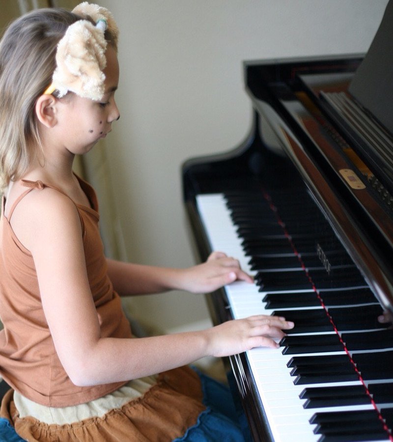 Side view of a young Caucasian girl playing the piano