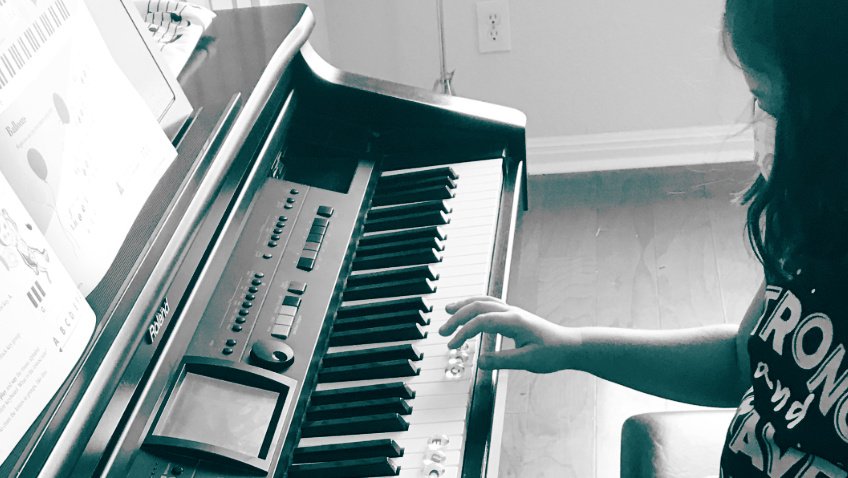 monochrome photo of a young girl playing the keys of an electric piano